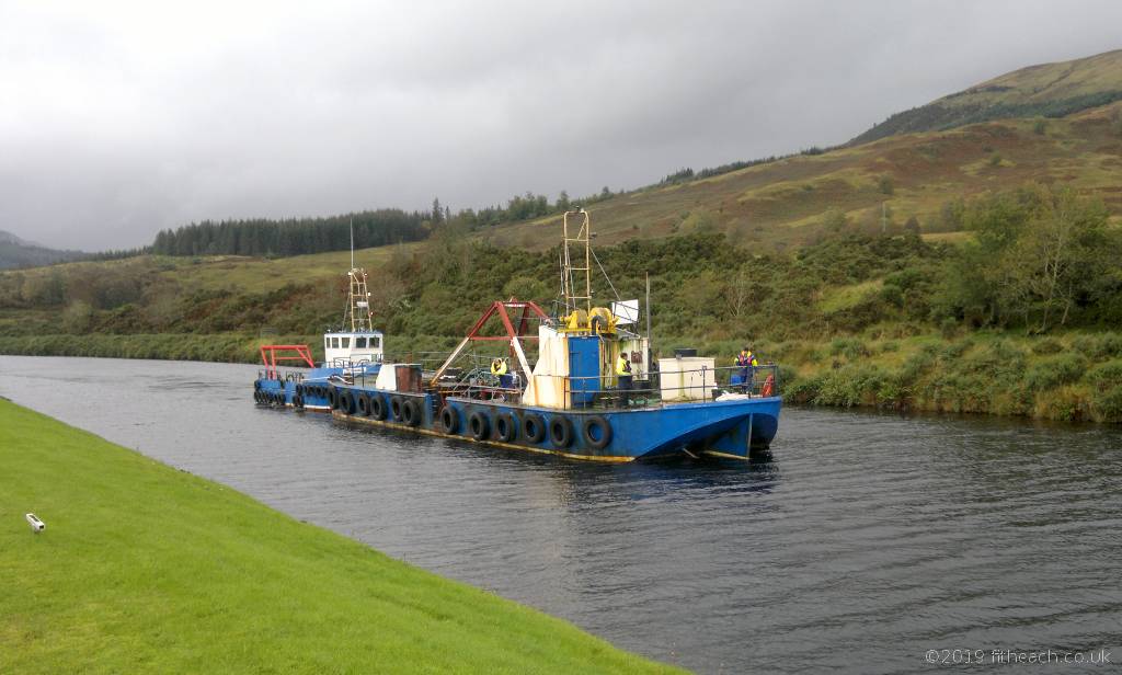 Two boats on the Caledonian Canal. One boat appeared to be towing the other.